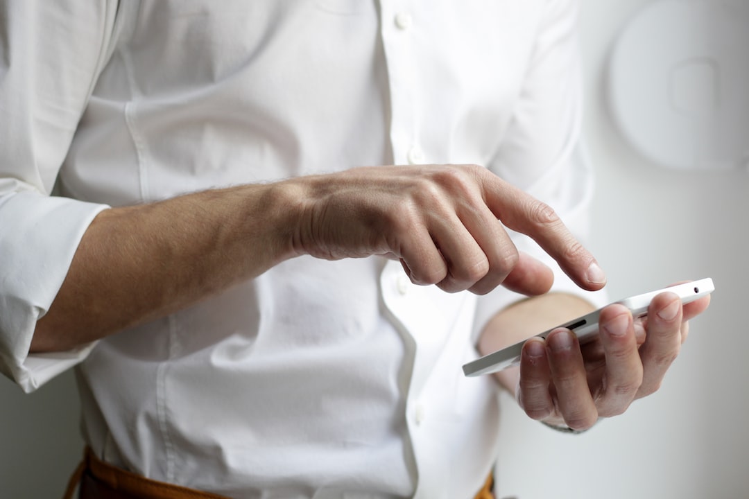 Homme avec chemise blanche et un téképhone cellulaire.